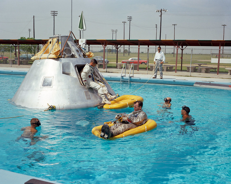 A group of people in the pool with an inflatable raft.